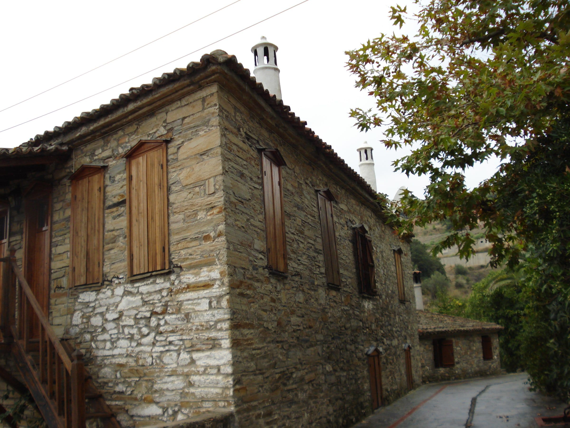Traditional stone house with wooden shutters in the old quarter of Nikiti