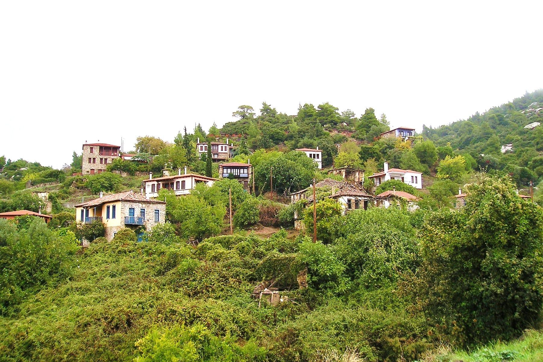 Stone and whitewashed houses among green hills in Parthenonas, Sithonia