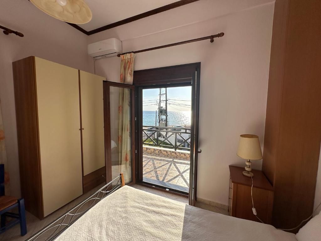 Bedroom with a full-size bed and open balcony door overlooking the sea at Villa Anastassia