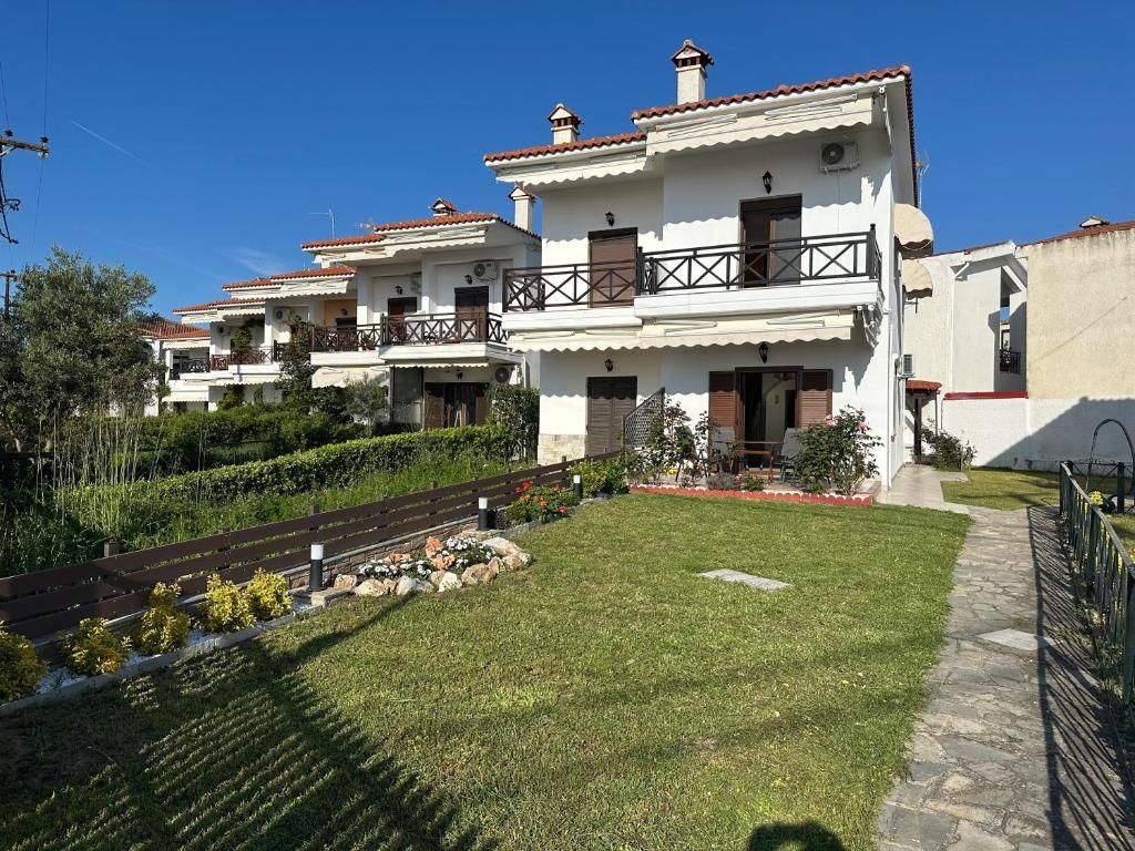 White exterior of Villa Anastassia beside its private lawn and flower garden