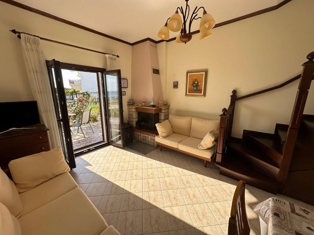 Bright living room at Villa Anastassia with sofas, wooden staircase and doors opening to the garden