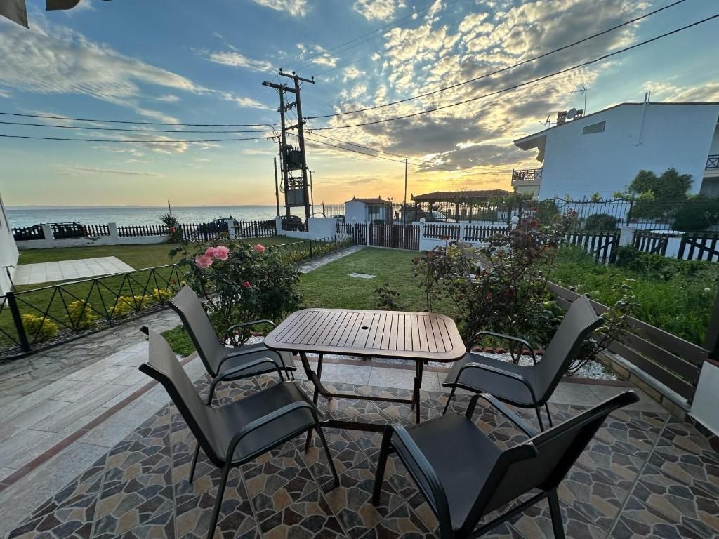 Outdoor dining table on the patio of Villa Anastassia overlooking the garden and Aegean Sea at golden hour